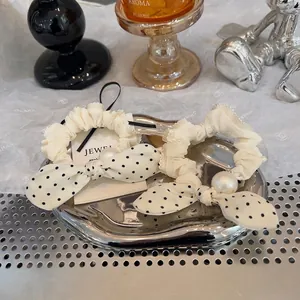Close-up of cream lace scrunchies featuring polka dot bows and elegant pearl accents