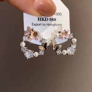 Detailed macro view of elegant butterfly wreath earrings with pink stars and pearls