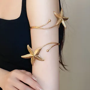 Detail view of a golden metal starfish arm cuff worn on the upper arm with texture.