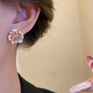 Close-up view of elegant 18k gold plated earring featuring zircons, pearls and a butterfly