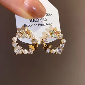 Detailed view of 18k gold-plated butterfly earrings with pearls and stars