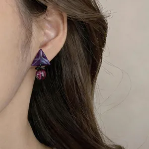 Primer plano de pendientes retro de resina con triángulo púrpura y cuenta roja