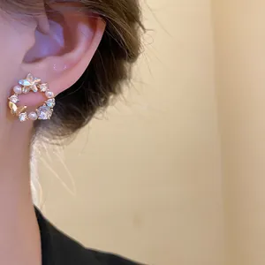 Close-up of 18k gold plated butterfly stud earrings with pearls and zircons on ear.