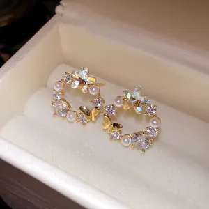 Close-up of 18k gold plated butterfly star stud earrings with pearls and cubic zirconia.