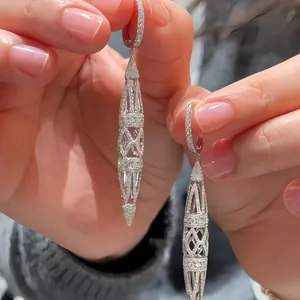 Detailed macro view of luxury hollowed-out rhombic drop earrings with pavé-set crystals