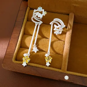 Detailed view of silver star tassel ear clips with yellow zircon in a wooden jewelry box.