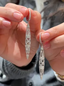 Close-up of elegant hollow geometric drop earrings with sparkling pave stones.