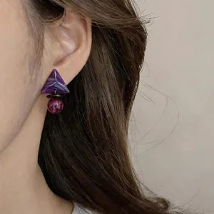 Detalle de pendientes vintage de resina con triángulo púrpura y cuenta roja