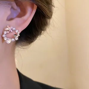 Close-up of elegant 18k gold plated butterfly stud earrings with sparkling zircons and pearls