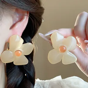 Detailed view of vintage resin flower stud earrings in beige with orange centers.
