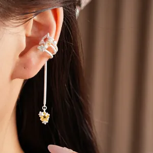Detail close-up of white star-shaped ear cuff with zircon and a long hanging tassel.