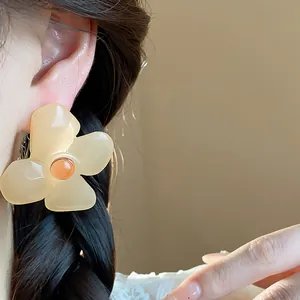 Close-up of cream resin flower stud earring worn on model's ear for elegant look