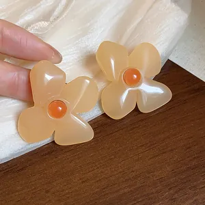 Close-up of retro resin flower stud earrings with elegant orange blossom design.