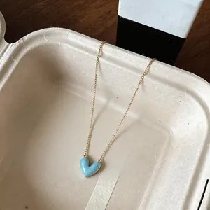Detailed macro shot of a light blue enamel heart pendant on a gold chain necklace