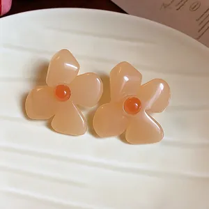 Detailed macro view of elegant peach resin flower stud earrings with orange centers.