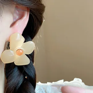 Close-up of vintage resin flower earring worn on model's ear with soft background