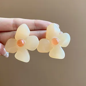Close-up of elegant cream resin flower stud earrings with vintage silver needles