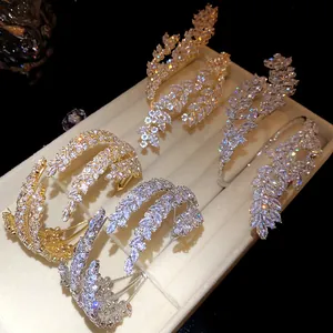 Close-up of zircon three-layer leaf crossover open bangles in gold and silver finish.