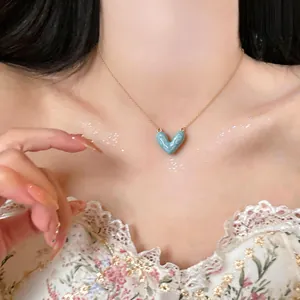 Close-up of a 14k gold plated necklace with a light blue enamel heart pendant