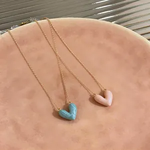 Close-up of 14k gold plated heart necklaces with pink and blue enamel pendants