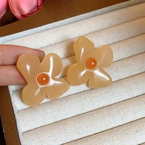 Close-up of retro amber resin flower stud earrings in a cream velvet jewelry display box