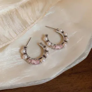 Elegant C-shaped silver stud earrings with small pearls and pink crystal flower details.