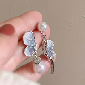 Elegant crystal butterfly earrings with white pearls on a stainless steel setting.
