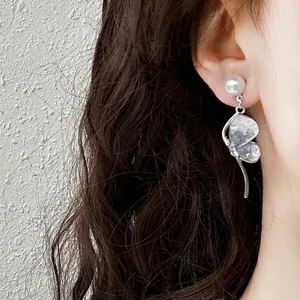Elegant Korean style crystal butterfly and pearl stud earrings displayed on a model's ear