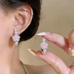 Macro detail of pink flower earrings with pearls and rhinestones on silver posts.