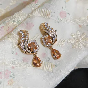 Detail view of vintage style gold-tone earrings with amber stones and white zircons