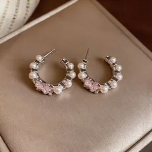 Detailed view of C-shaped hoop earrings featuring pink floral enamel and white pearls