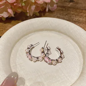 Detailed view of elegant silver C-shaped hoop earrings with pink enamel flowers and pearls