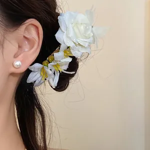 Detailed view of elegant white rose flower hair stick and pearl stud earring on hair style.