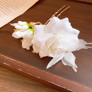 Detailed close-up of white fabric rose hairpin featuring delicate water droplets on petals