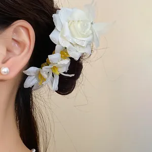 Detail of elegant white floral hairpins styled in a bun with a pearl earring.