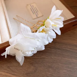 Close-up detail of white fabric flower hair pins with delicate water drop accents
