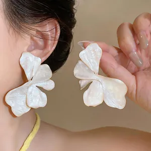 Detailed macro view of elegant white marble flower earrings with gold-toned metal edges