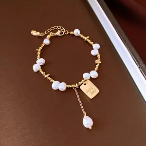 Close-up detail of 18K gold-plated bracelet featuring baroque pearls and Good Luck tag