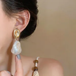 Close-up of French vintage irregular baroque pearl drop earrings worn by a model