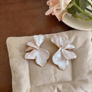 Detailed macro view of oversized pearlescent flower stud earrings with gold edges