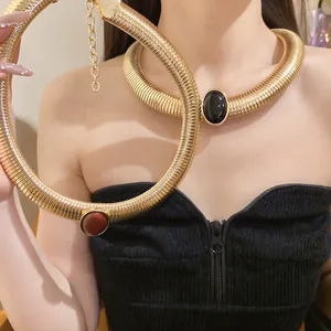 Macro detail of vintage gold-toned metal choker with black oval resin gemstone.