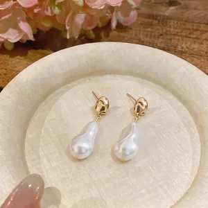 Close-up view of elegant French vintage gold earrings featuring unique irregular baroque pearls