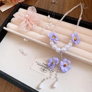 Macro detail of sweet purple chiffon flower and white pearl necklace in a display box