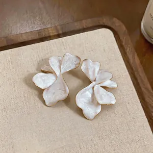 Close-up of elegant oversized flower stud earrings with pearlescent white drip-oil finish
