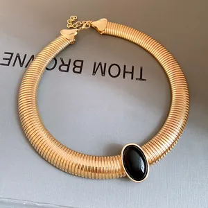 Close-up of vintage gold metallic choker with central black oval resin stone inlay.