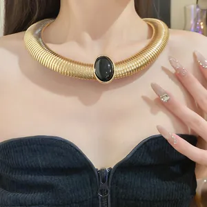 Detail of vintage gold-toned ribbed metal choker with a large black oval resin centerpiece.