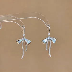 Eleganti orecchini a fiocco color argento con pietre luccicanti su sfondo marrone