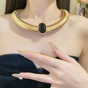 Detailed close-up of a vintage gold metal collar necklace with a black resin oval stone