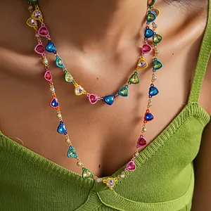 Close-up of colorful enamel heart necklace with sparkling crystals on a green knit top