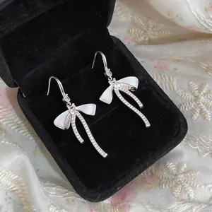 Primo piano di orecchini a fiocco eleganti con pietre brillanti in una scatola da regalo